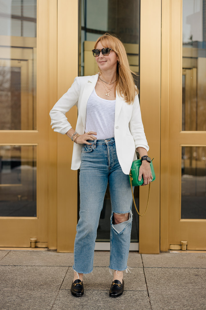 Wearing the Cinq à Sept Khloe blazer in white with REDONE jeans, black Gucci Joordan loafers, and an emerald green Clare V. crossbody bag.