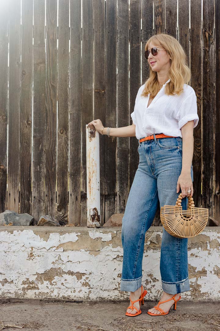 Wearing the XiRENA Cruz shirt in white with MOTHER tunnel vision jeans, and Frame belt and heels in the color orange crush.