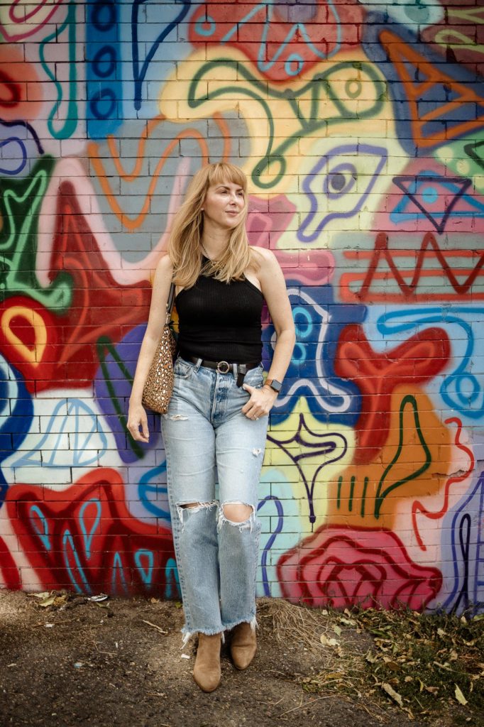 Wearing the black LNA ribbed tank top with distressed Moussy Odessa jeans and camel Rag and Bone booties in front of a graffiti wall.