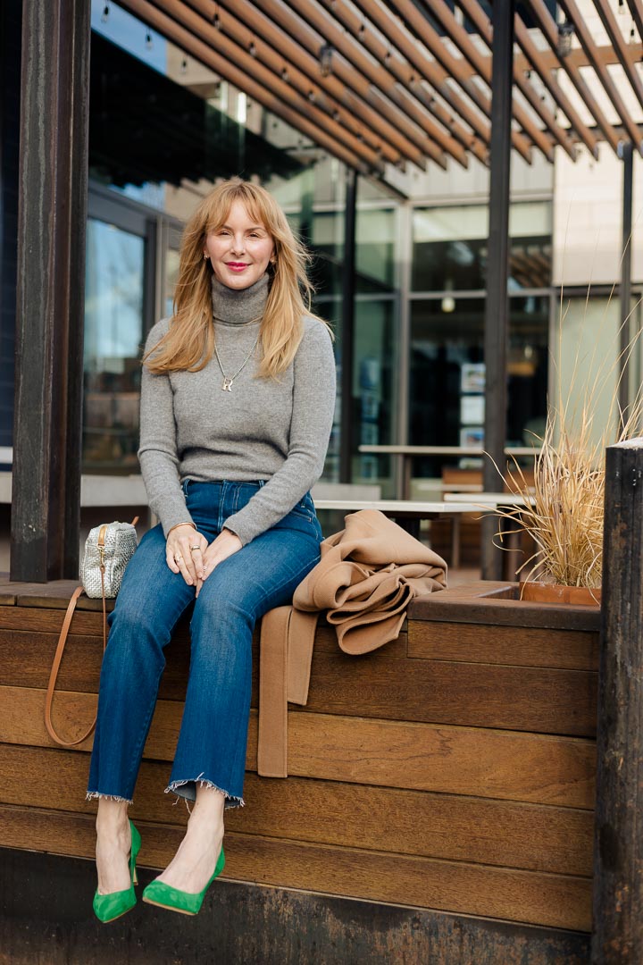 Wearing a gray cashmere Equipment turtleneck with Mother Hustler jeans and green L'agence Eloise pumps.