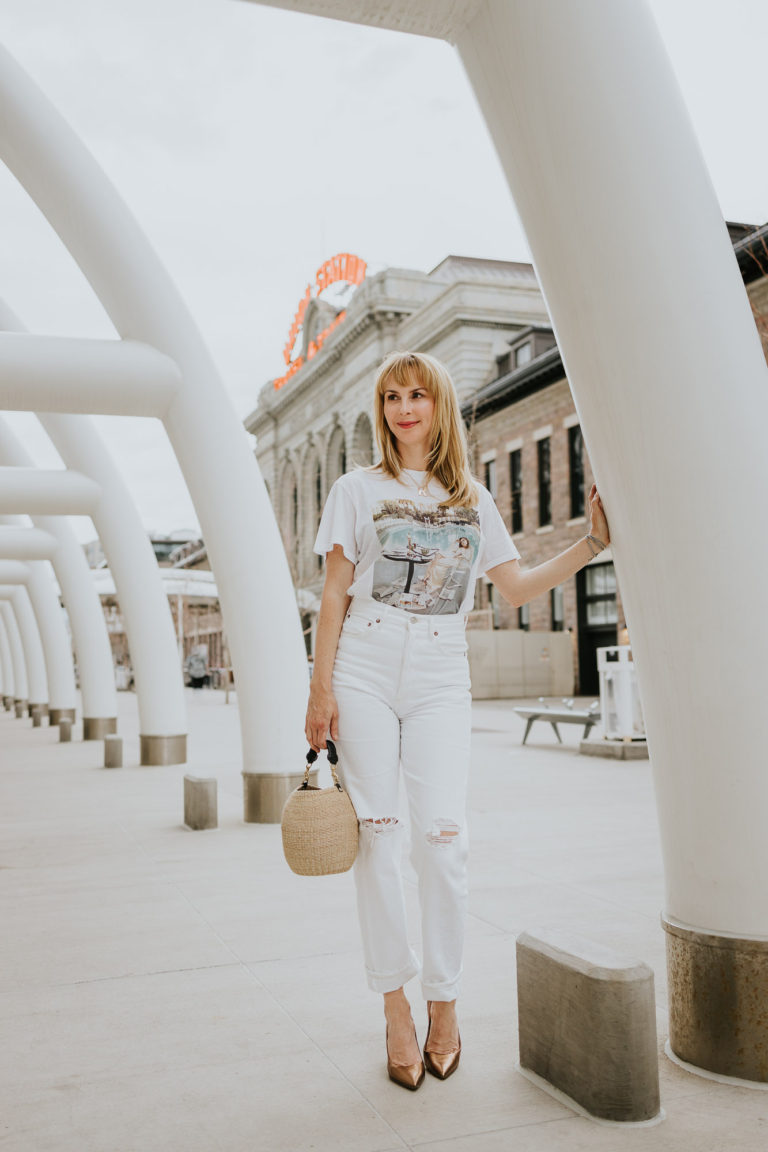 Standing in front of Union Station in Denver wearing white Agolde 90s jeans and a white Anine Bing graphic tee.