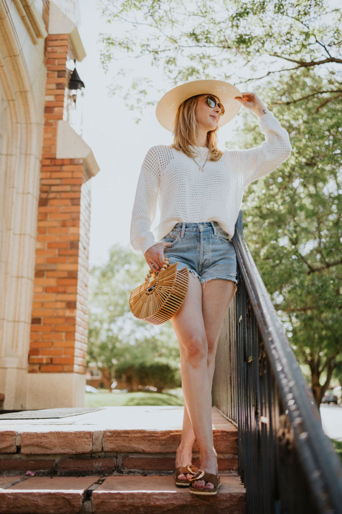 Wearing a Sweaty Betty open weave sweater with a wide brim hat and cutoff shorts on a sunny day.