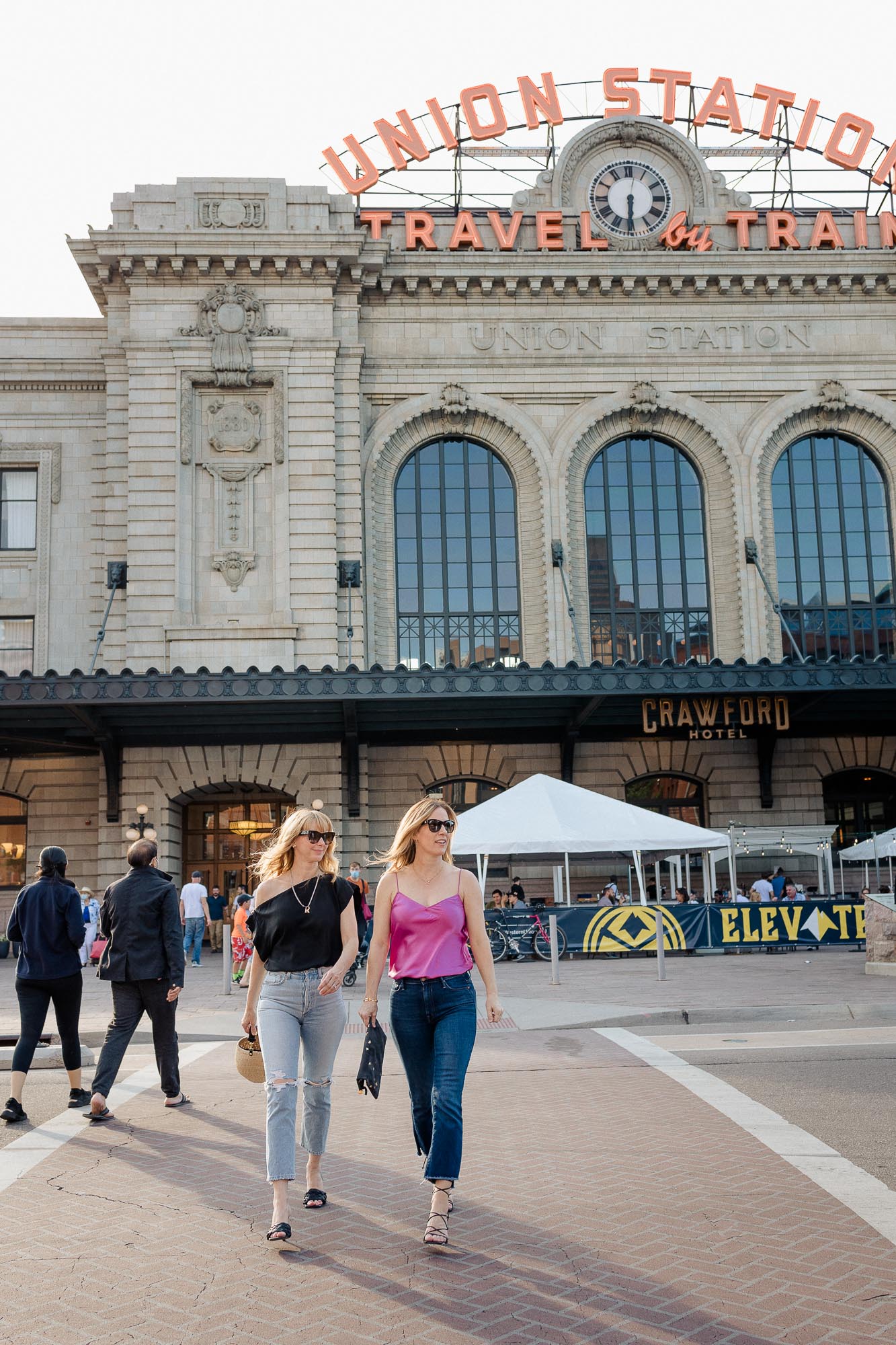 Rachel & Tammy walking out of Union Station in Denver wearing a pink camisole and black top.