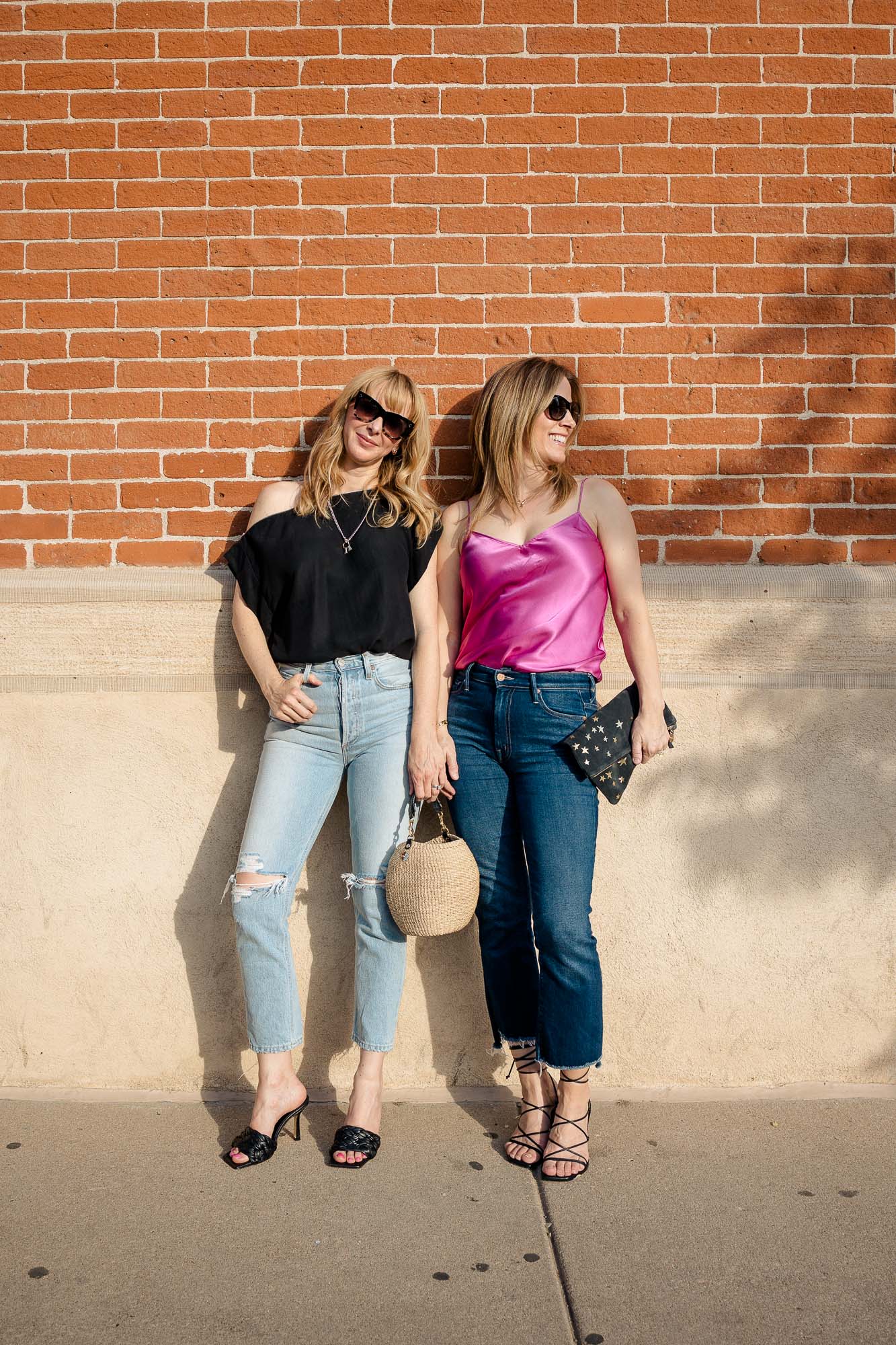 Tammy & Rachel in front of a brick wall in Denver wearing a pink Paige camisole and black off the shoulder top.