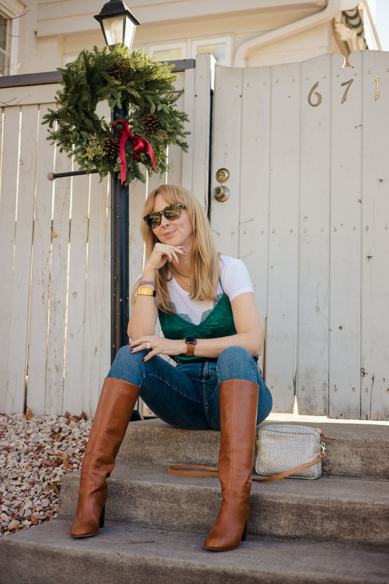 Wearing and emerald green silk camisole by Cami NYC over a white tee shirt with jeans and cognac Loeffler Randall Goldy boots.
