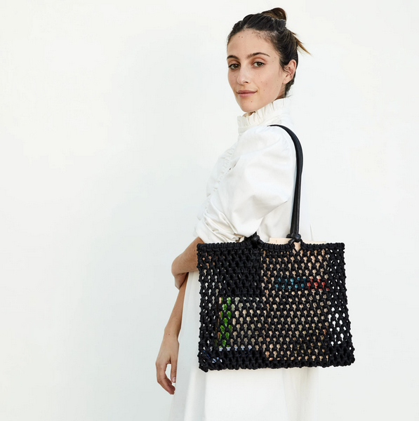 Woman holding the Clare V. Sandy bag in black.