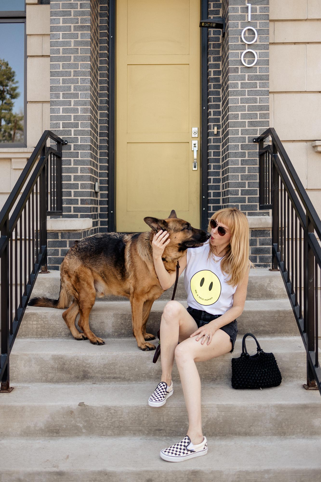 Sitting on the steps with german shepherd in the Le Superbe 'Just Be Nice' smiley face tee.