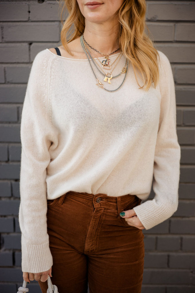 Wearing Marla Aaron necklaces and locks with a cream cashmere Naked sweater.