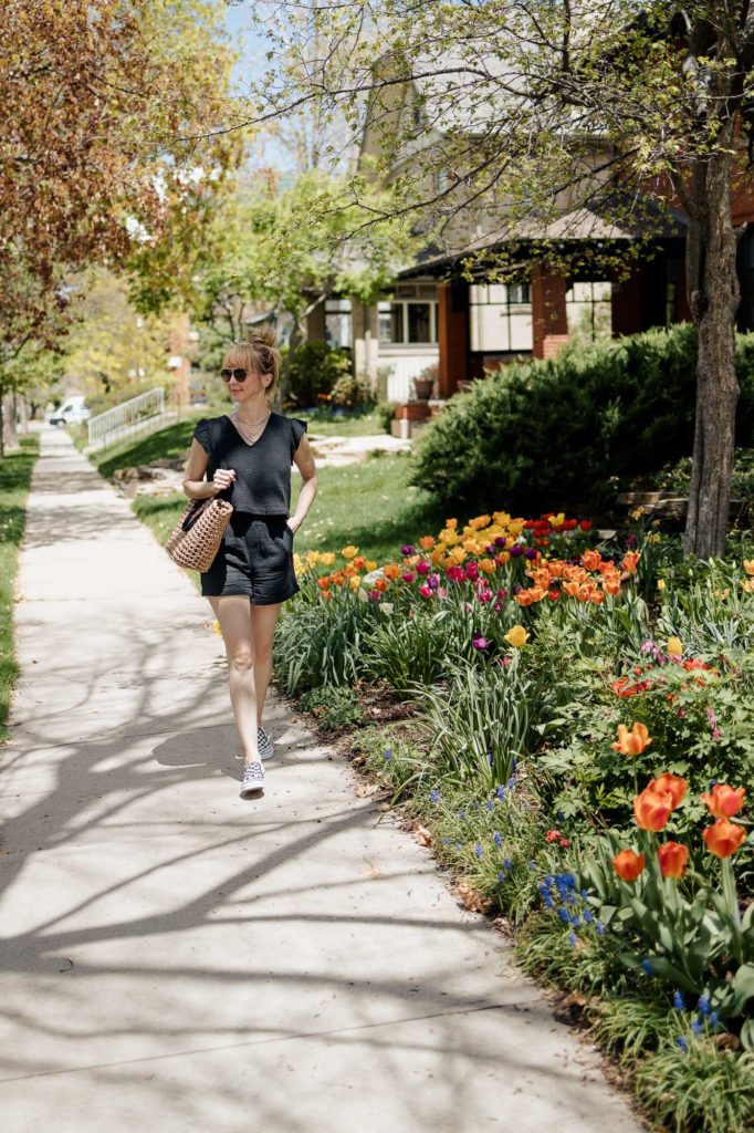 Walking by colorful tulips in a black Rails short set, sandals, and straw tote.