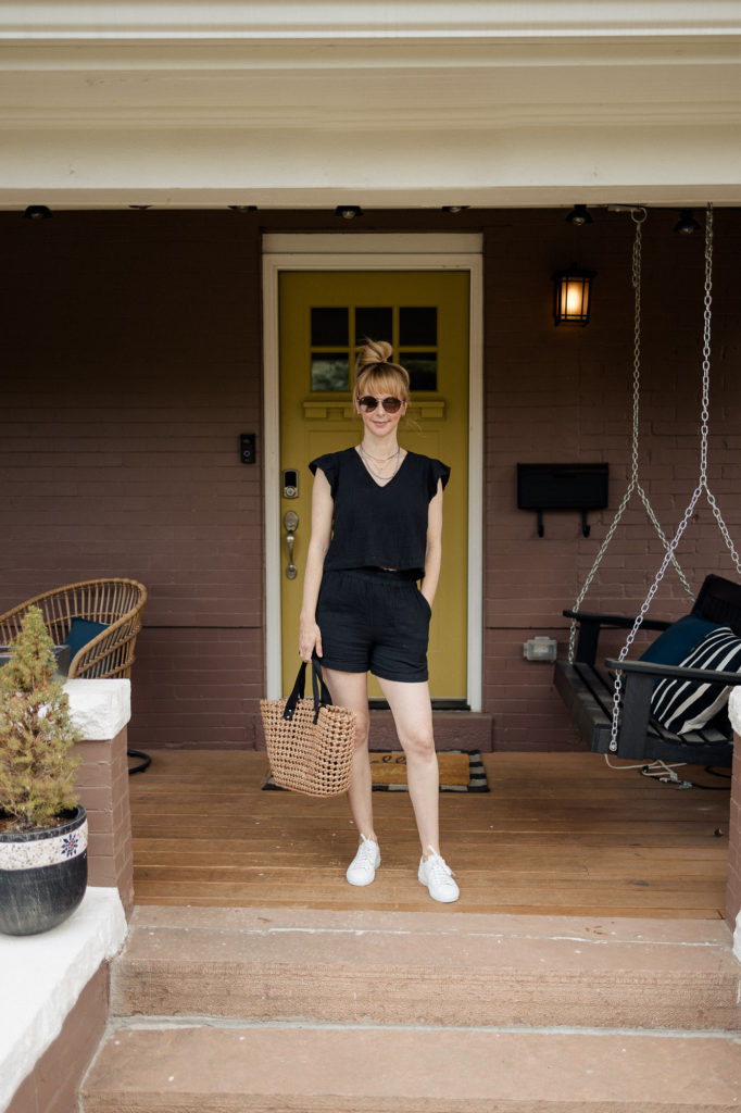 Wearing a black Rails short set with white Axel Arigato sneakers and a straw tote.