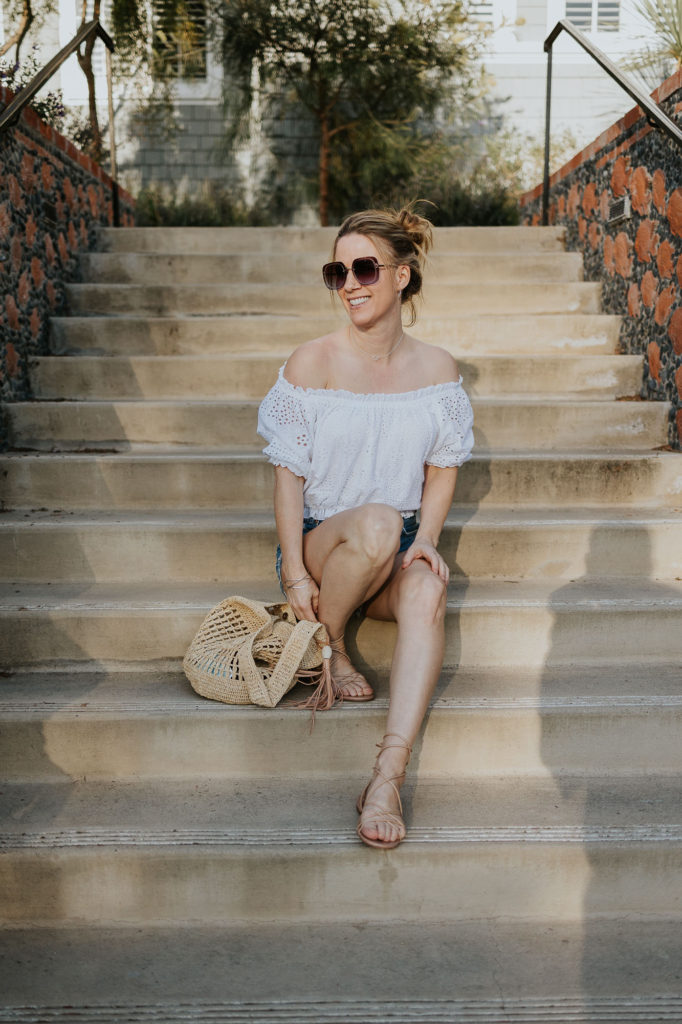 Girl on stairs in Encinitas with white off the shoulder top.