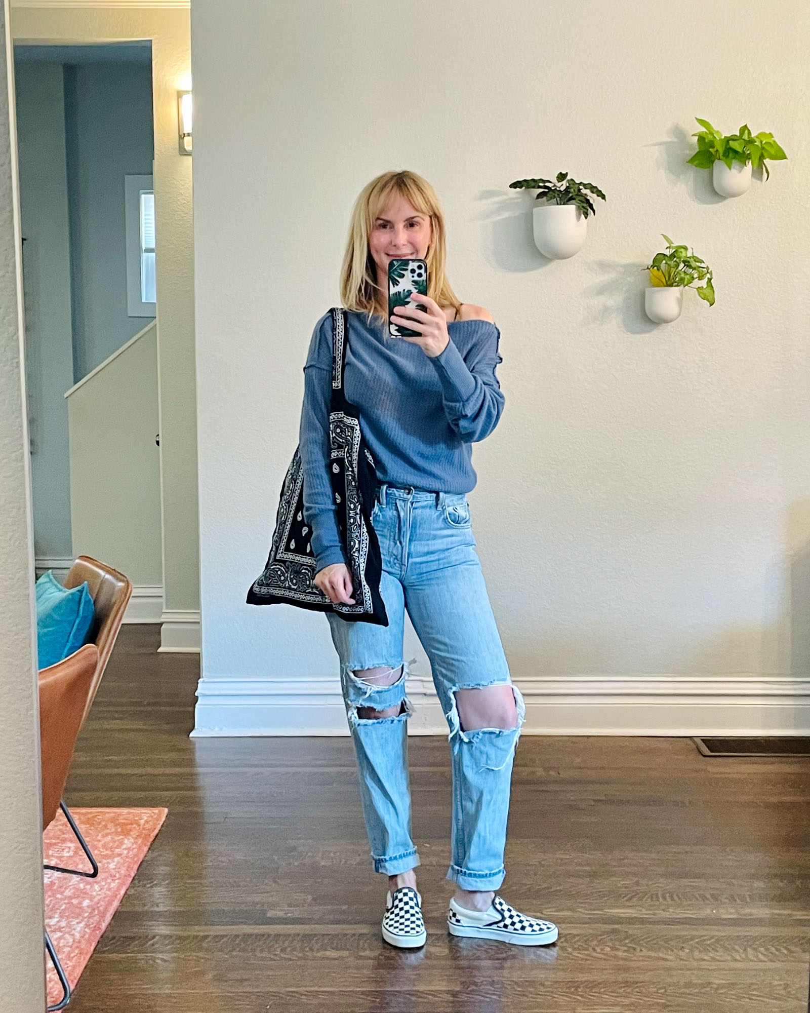 Wearing the Treasure and Bond off the shoulder top in blue with ripped jeans, vans checkered sneakers, and an Arizona Love black bandana tote bag.