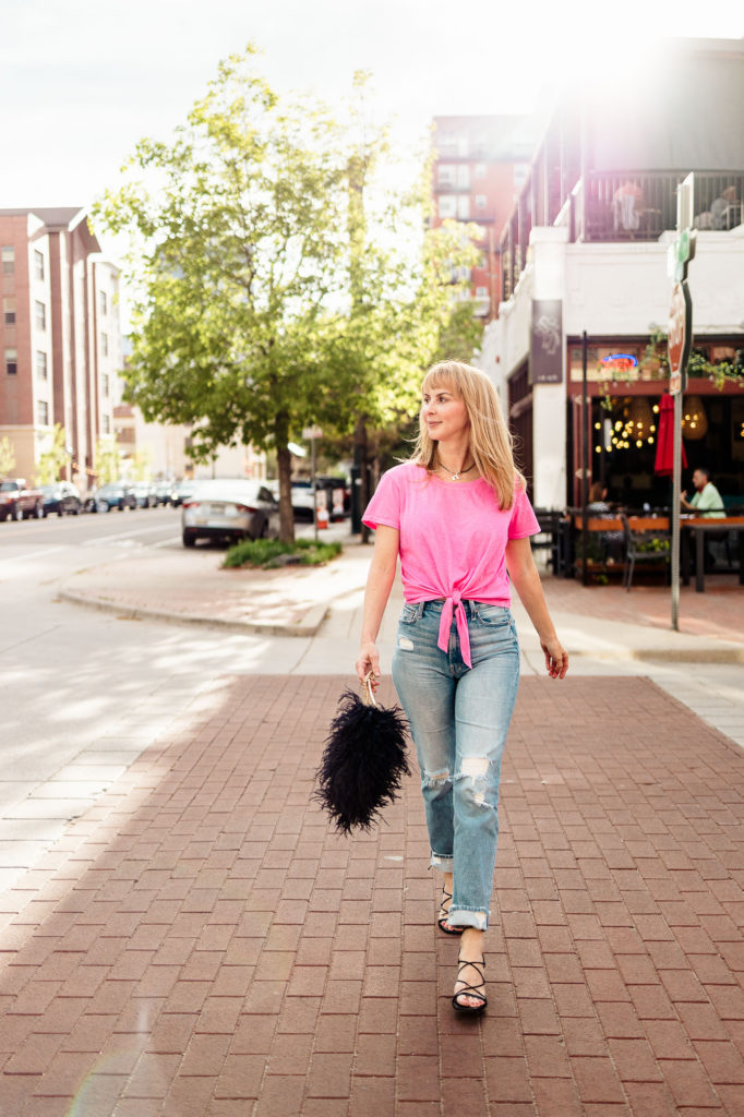 Crossing the street in a Sundry hot pink tee, distressed Mother jeans, Frame heels and a feather bag.