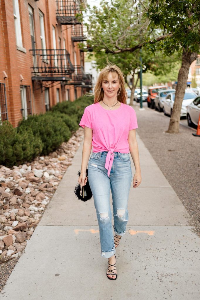 Walking down the sidewalk in a hot pink Sundry tee, distresses jeans, Frame heels and a feather bag.