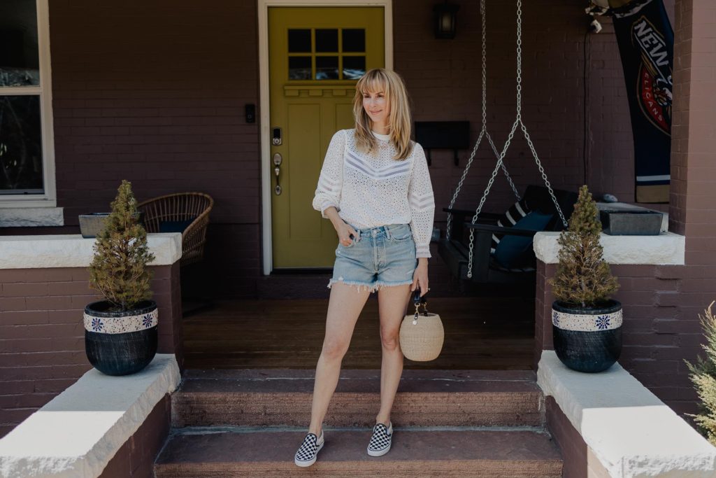 My favorite spring outfit includes the Reiss Naina eyelet top in white, Agolde Parker cutoff denim shorts, classic checked vans, and the Clare V Pot de Miel in cream.