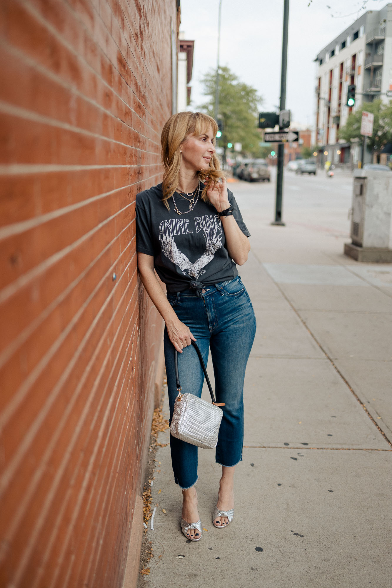 Wearing the Anine Bing washed black eagle graphic tee with Mother jeans and a silver bag and pumps.