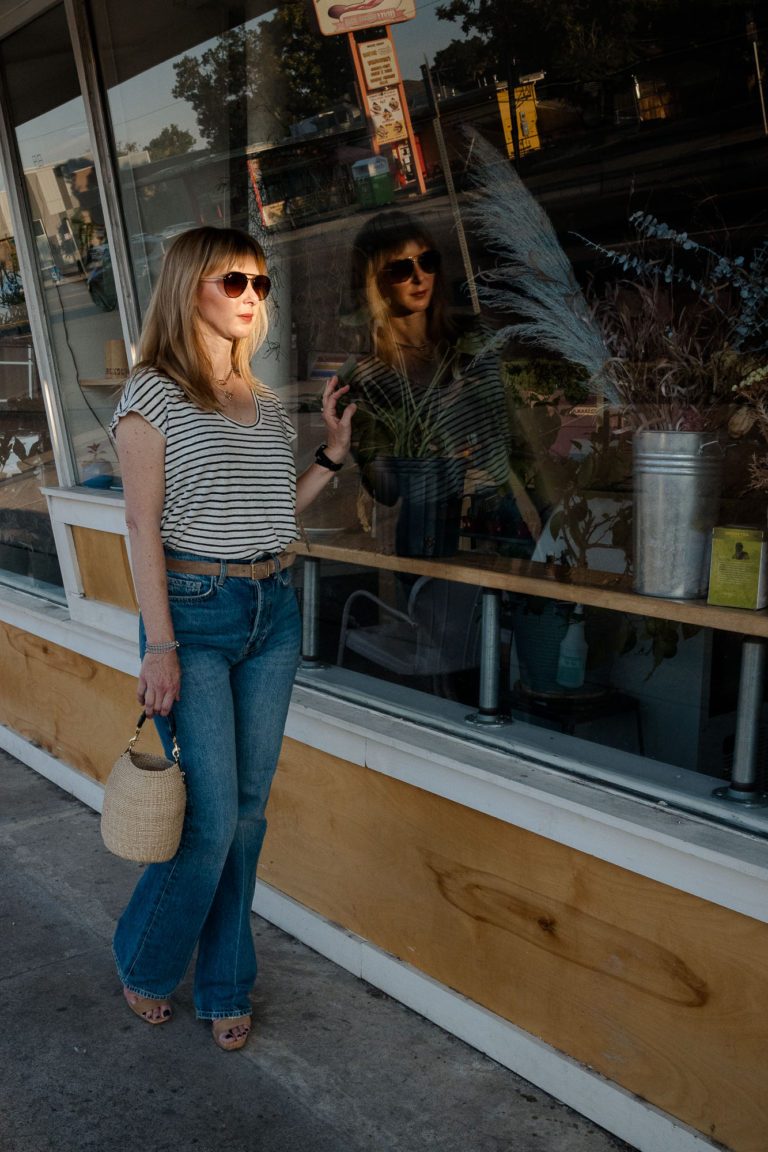 Wearing the Anine Bing Bryn jeans with a black and white striped Fame linen tee looking in the window of a coffee shop.