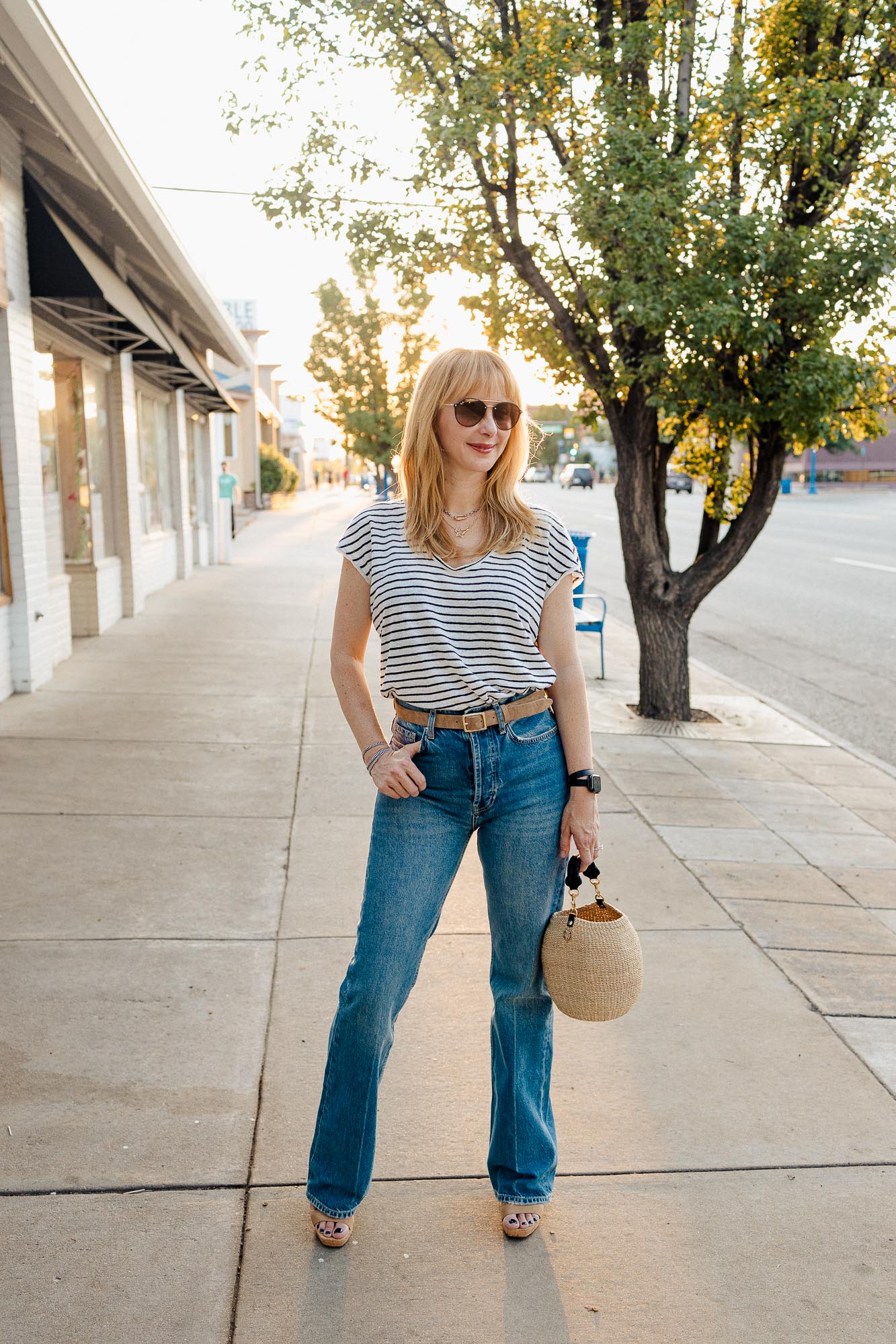 Wearing the Anine Bing Bryn bootcut jeans with a black and white striped linen Frame top, taupe belt, heels and Clare V pot de miel.