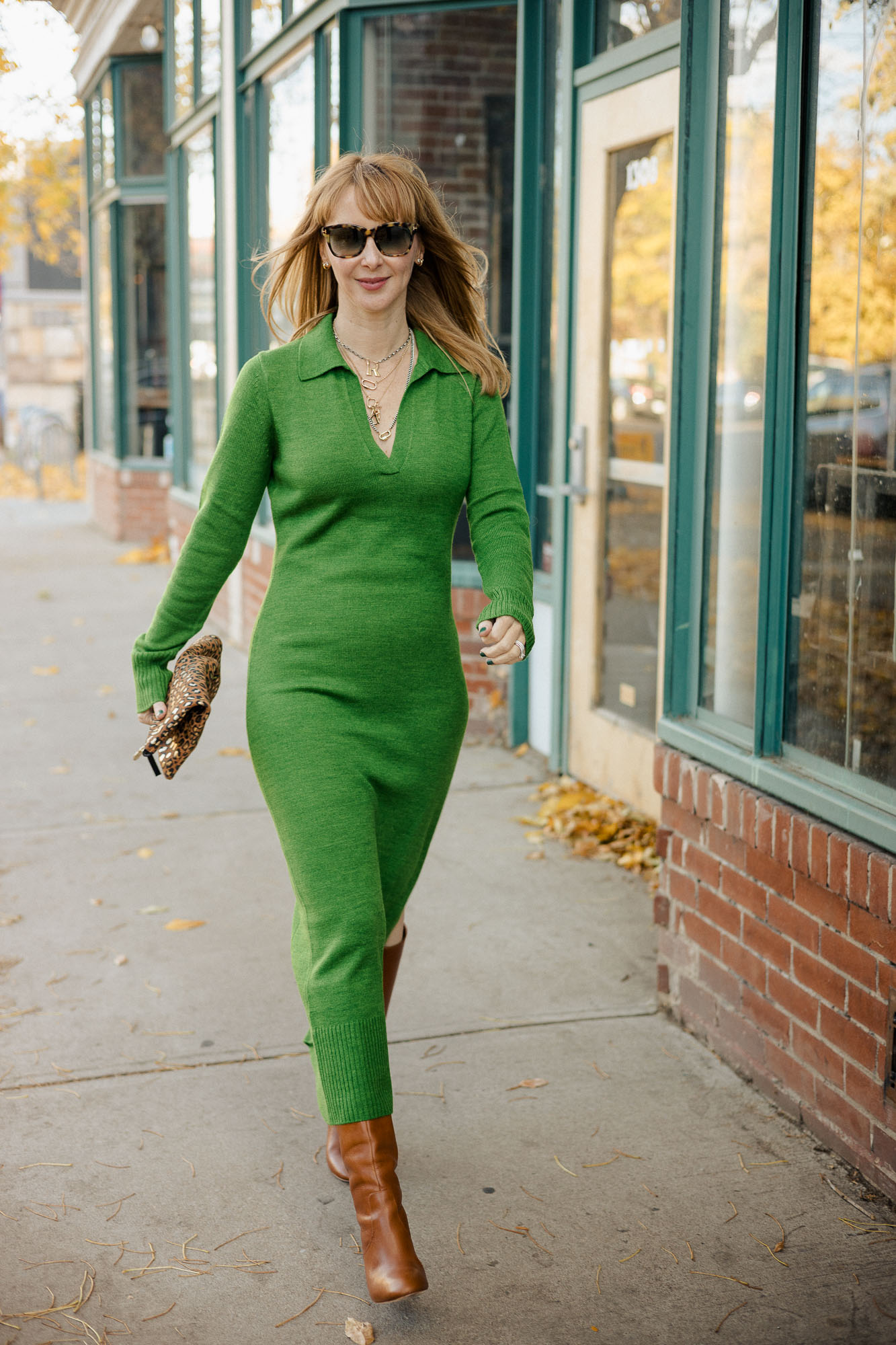 Walking down the street wearing a midi ddress by Staud in emeraldd green Loeffler Randall goldy boots in cognac and a Clare V leopard clutch.
