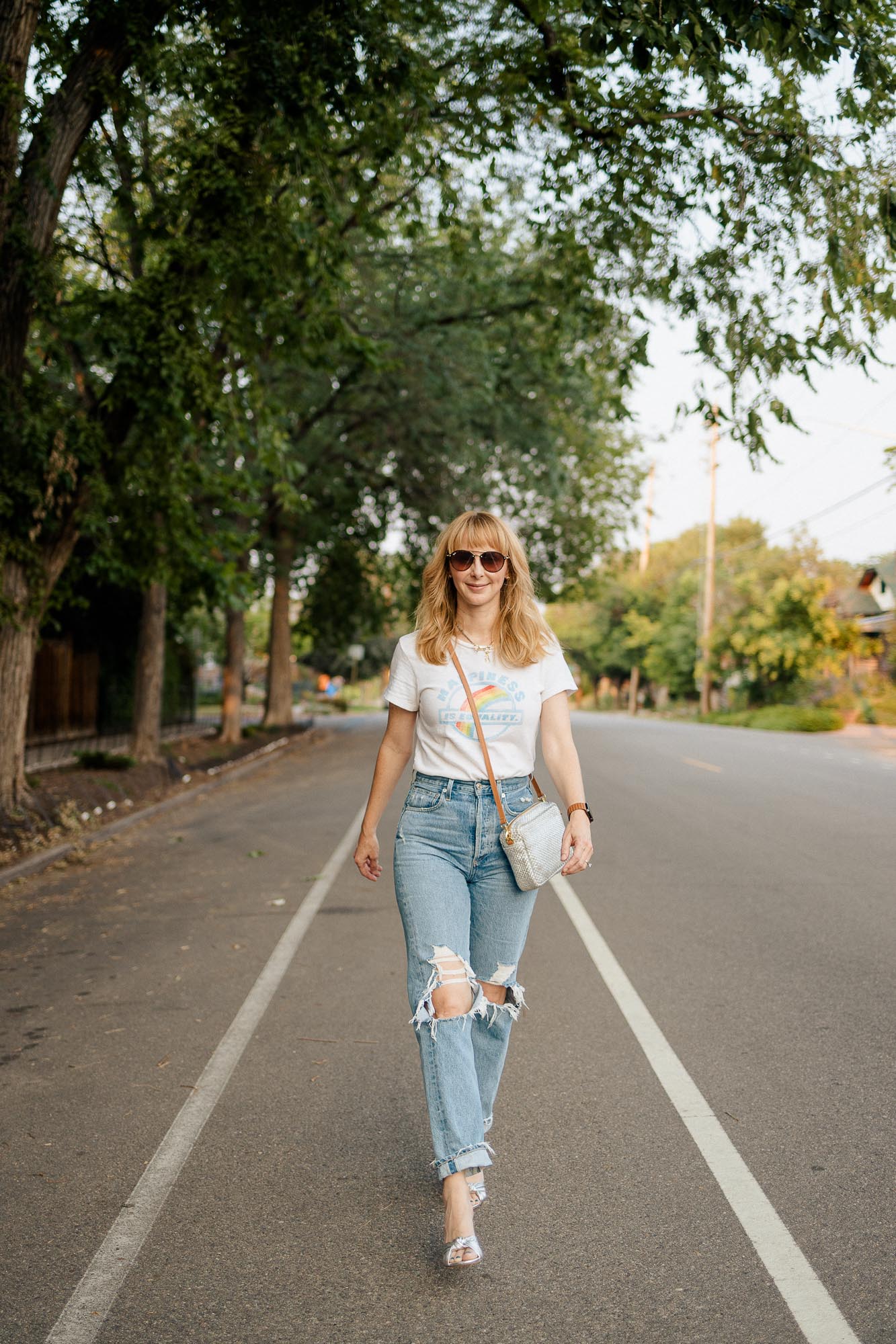 Walking down the street wearing Agolde 90s jeans, a Redone tee, Veronica Beard silver granita heels, and a silver Clare V crossbody bag.