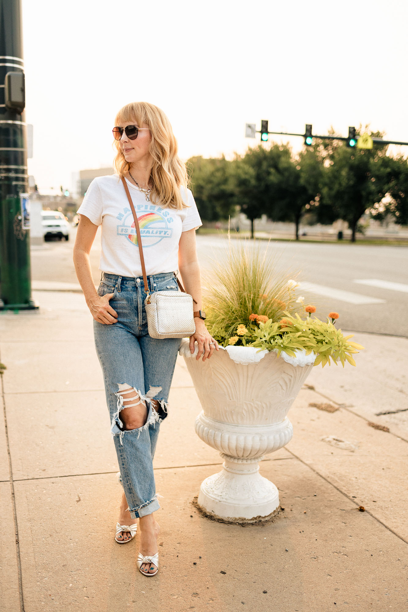 Standing on Colfax wearing distressed Agolde 90s jeans, a silver clare V bag, and silver Veronica Beard heels.
