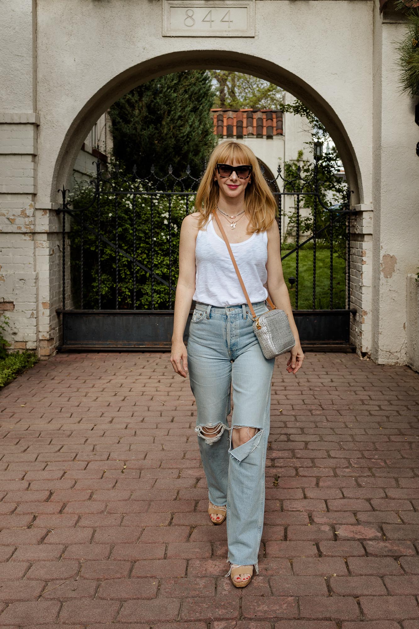 Wearing a Veronica Beard white tank with Re/Done ripped 90s jeans and a silver Clare V bag with Celine sunglasses.